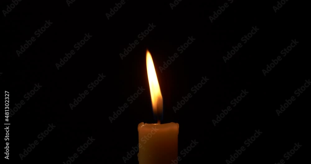 Close-up burning single candle flame isolated on black background, 4K video Close-up burning single candle flame isolated on black background, 4K video