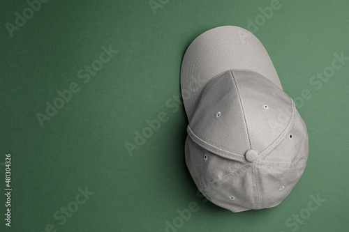 Canvas Print Stylish grey baseball cap on dark green background, top view