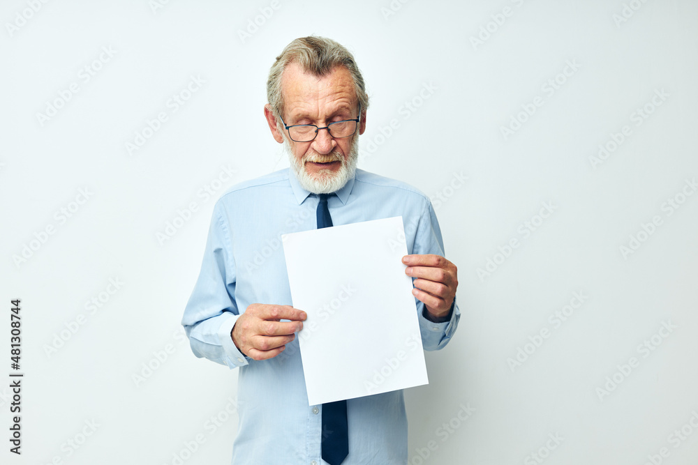 Photo of retired old man holding documents with a sheet of paper light background Photo of retired old man holding documents with a sheet of paper light background