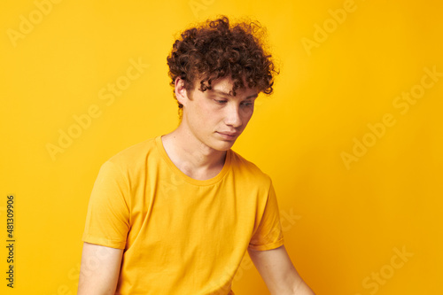 Young curly-haired man Youth style glasses studio casual wear yellow background unaltered © Tatiana