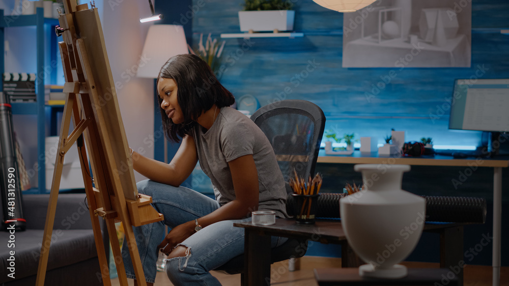 Artist of african american ethnicity drawing white vase design on canvas with pencil sitting in art studio at home. Black young woman getting authentic inspiration for modern masterpiece Artist of african american ethnicity drawing white vase design on canvas with pencil sitting in art studio at home. Black young woman getting authentic inspiration for modern masterpiece