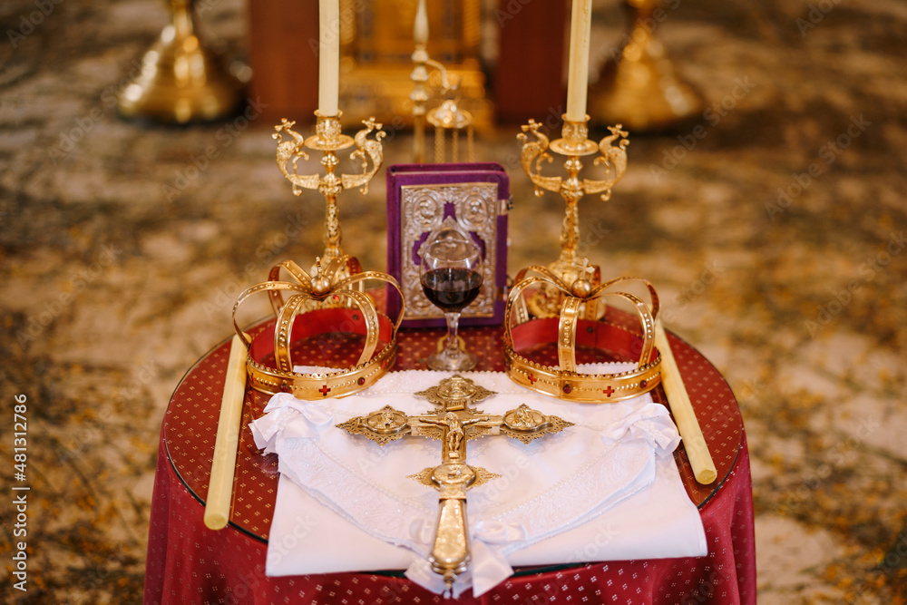 Cross, golden crowns and candlesticks stand on the table in the church