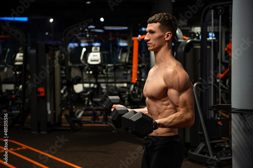 Shirtless man doing bicep tricep curls with dumbbells in gym, strength workout