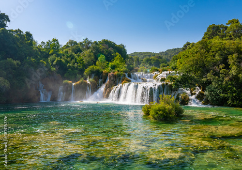 Waterfalls at Skradinski Buk, national nature park Krka, Croatia. Flowing water in beautiful nature, green plants and trees. Sunny summer day.