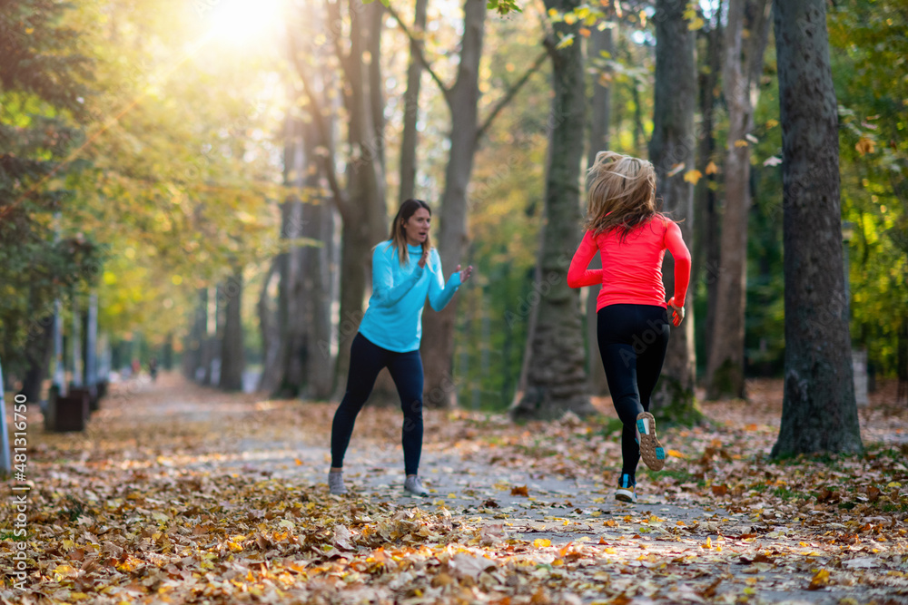 Woman Exercising in Public Park with Personal Trainer. Trainer Cheering and Woman Running Woman Exercising in Public Park with Personal Trainer. Trainer Cheering and Woman Running