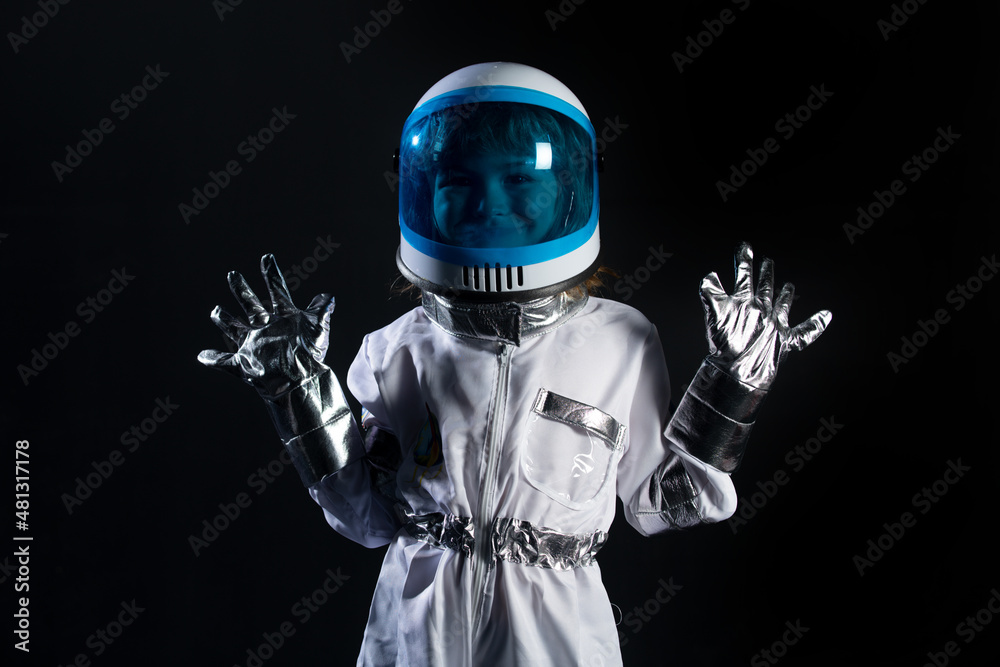 Small child wants to fly an in space wearing an astronaut helmet on black. Copy space. Small child wants to fly an in space wearing an astronaut helmet on black. Copy space.