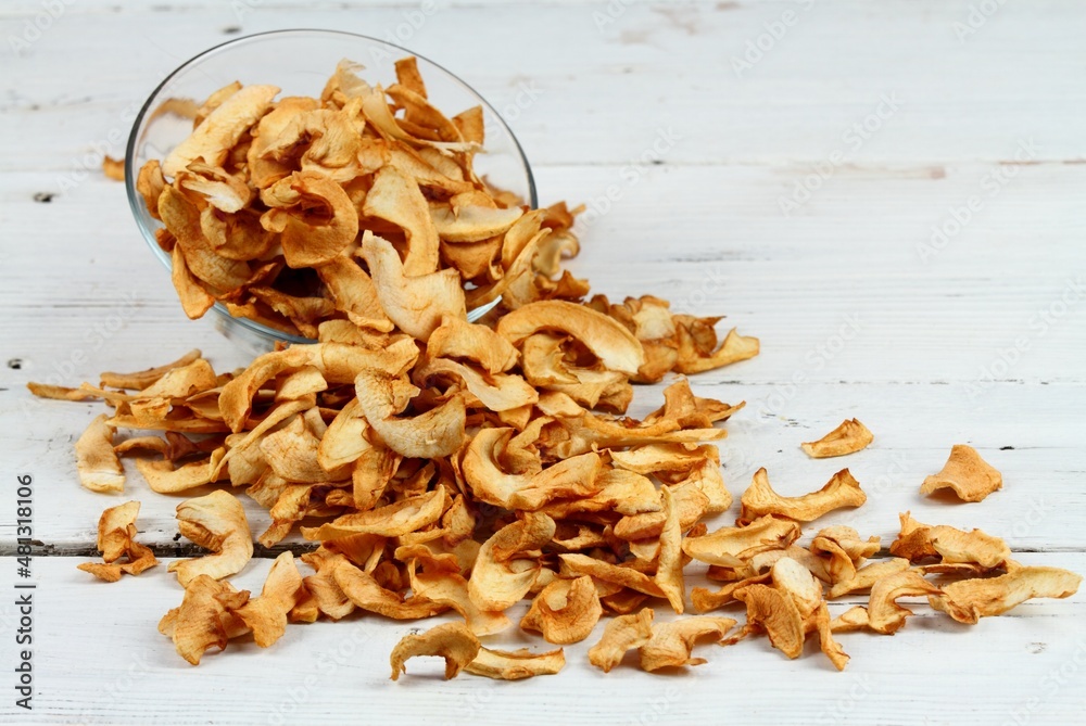 Homemade dried apples in a bowl. Dehydrated apple chips without peels on the white wooden table. Homemade dried apples in a bowl. Dehydrated apple chips without peels on the white wooden table.