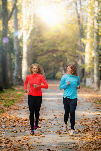 Woman Exercising in Public Park with Personal Trainer. Jogging Together in the Fall.