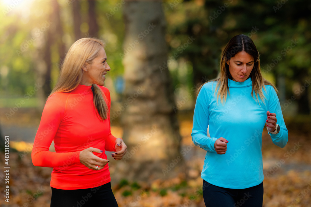 Woman Exercising in Public Park with Personal Trainer. Jogging Together in the Fall. Woman Exercising in Public Park with Personal Trainer. Jogging Together in the Fall.