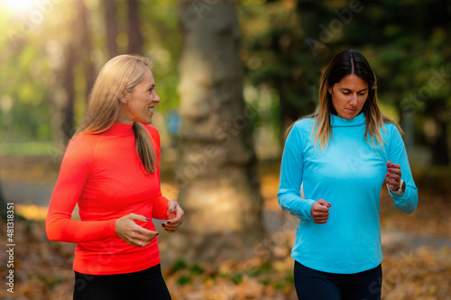 Woman Exercising in Public Park with Personal Trainer. Jogging Together in the Fall.