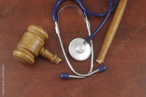 Broken judge gavel and stethoscope on wooden background. Malpractice and medicine out of law concept