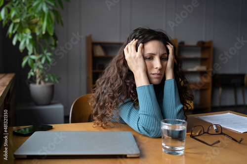 Frustrated businesswoman exhausted sit with closed laptop tired of trying to find solution to problem, searching for new ideas or inspiration. Stressed overworked girl suffer from professional burnout photo