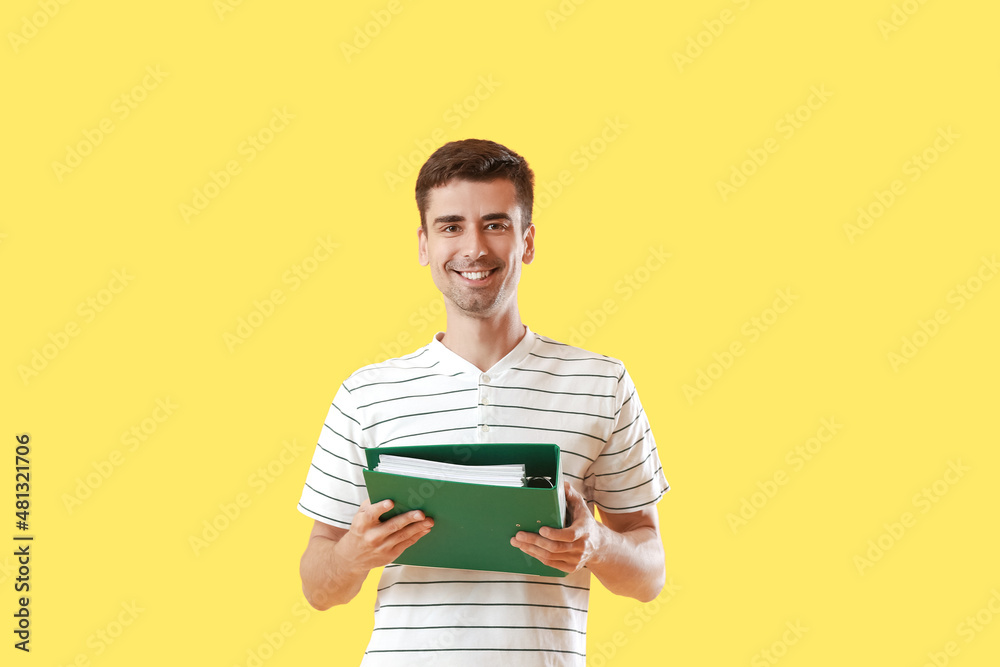 Young man with folder on yellow background Young man with folder on yellow background