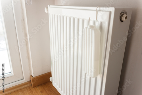Wallpaper Mural Heating radiator at home. Water pot is hanging on radiator for moistening.  Torontodigital.ca