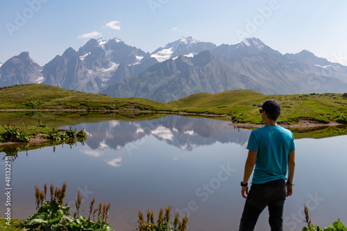 A man at the Koruldi Lake with an amazing view on mountain ridges near Mestia in the Greater Caucasus Mountain Range, Upper Svaneti, Country of Georgia. Reflection in the water. Wanderlust. Trekking