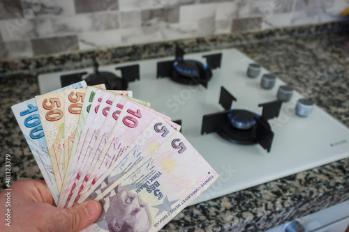 Fototapeta Naklejka Na Ścianę i Meble -  Turkey economic crisis. Turkish lira depreciates. Natural gas price raise. The man is holding Turkish paper banknotes. Stove at the background. Home economics concept.