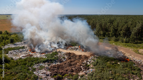 Photo of garbage dump in fire. Burning rubbish polluting the air by dangerous toxic gases.