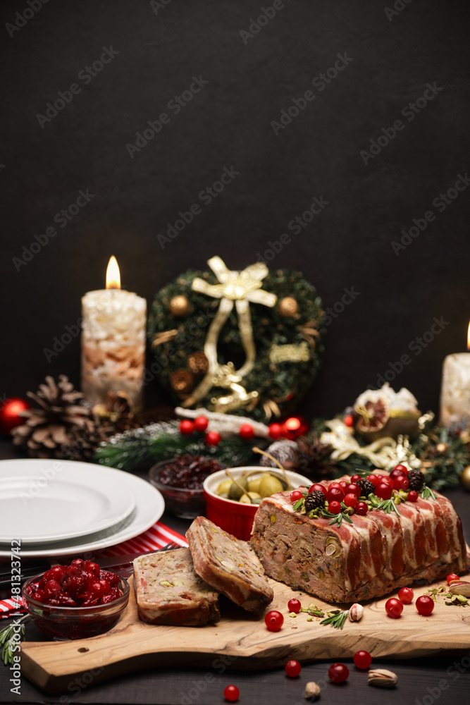 Traditional French terrine covered with bacon on dark wooden background with Christmas decorations