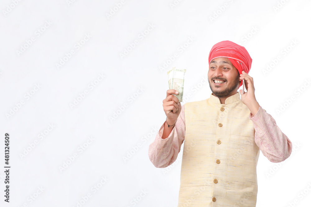 Young indian farmer talking on smartphone and showing money on white background. Young indian farmer talking on smartphone and showing money on white background.