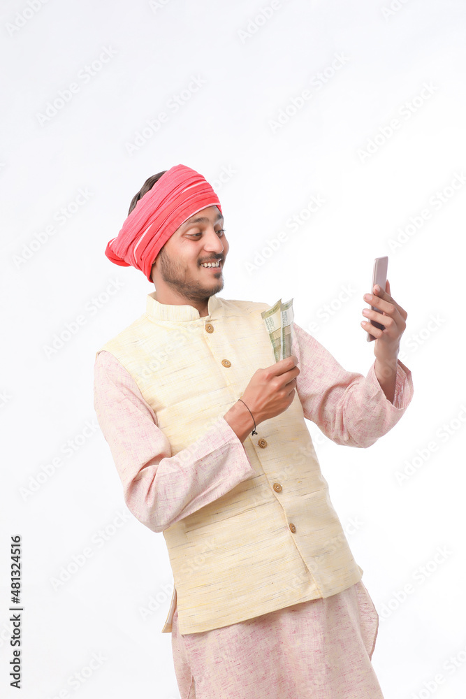Young indian farmer using smartphone and showing money on white background. Young indian farmer using smartphone and showing money on white background.