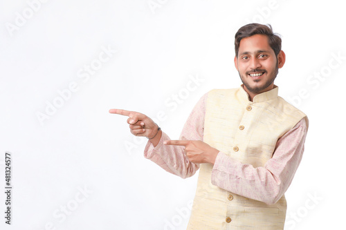 young indian man in traditional wear and showing direction on white background.
