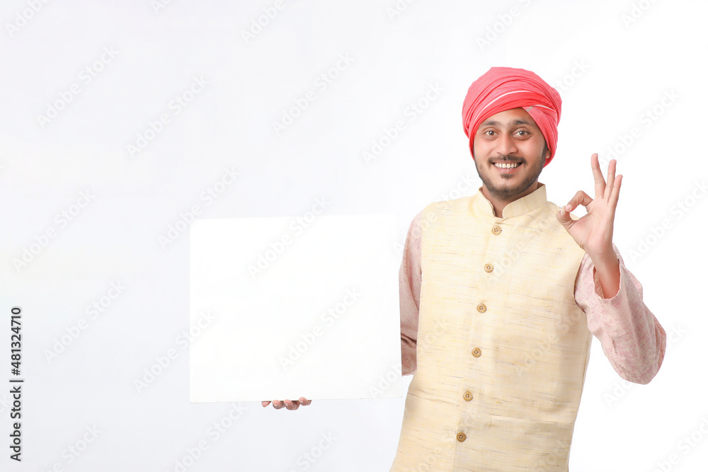 Indian man holding white board, promoting offers on festival season while wearing traditional cloths, standing over white background. Indian man holding white board, promoting offers on festival season while wearing traditional cloths, standing over white background.