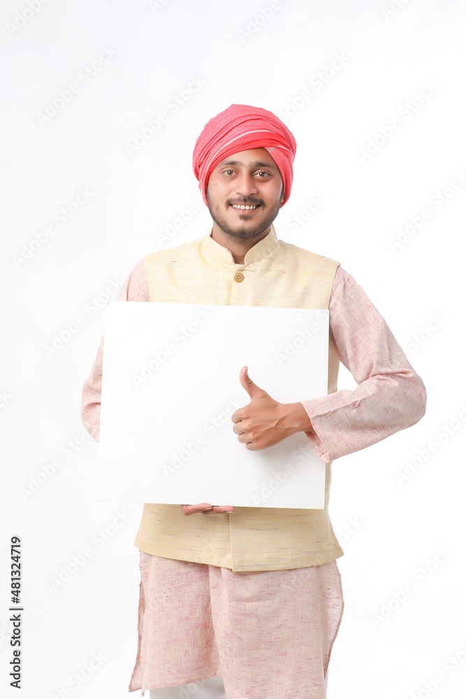 Indian man holding white board, promoting offers on festival season while wearing traditional cloths, standing over white background. Indian man holding white board, promoting offers on festival season while wearing traditional cloths, standing over white background.