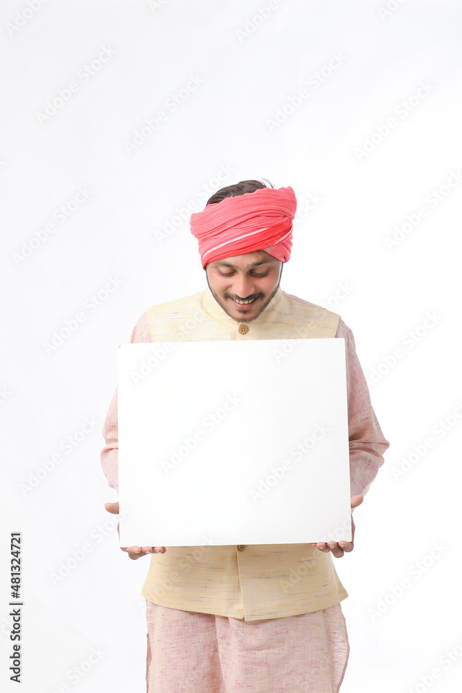 Indian man holding white board, promoting offers on festival season while wearing traditional cloths, standing over white background. Indian man holding white board, promoting offers on festival season while wearing traditional cloths, standing over white background.