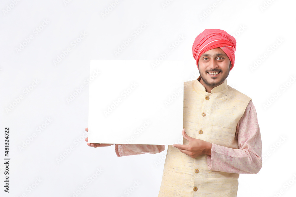 Indian man holding white board, promoting offers on festival season while wearing traditional cloths, standing over white background. Indian man holding white board, promoting offers on festival season while wearing traditional cloths, standing over white background.