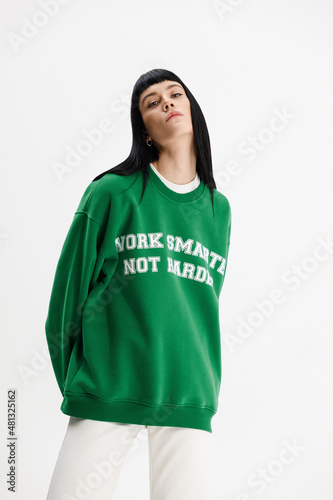 Studio photoshoot of a young brunette woman wearing casual clothing against a white background.  Natural makeup and hairstyle