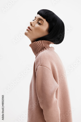 Studio photoshoot of a young brunette woman wearing casual clothing against a white background.  Natural makeup and hairstyle