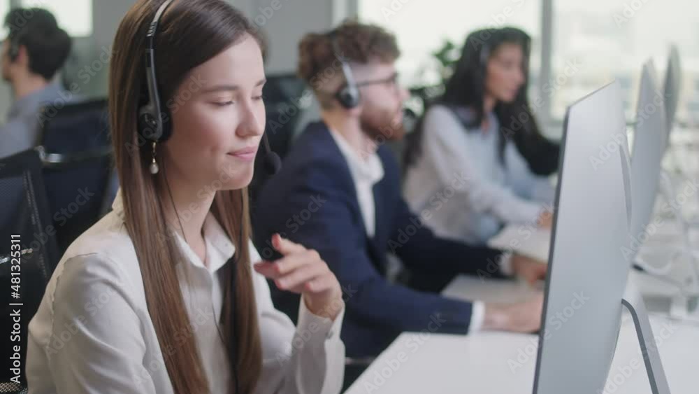 Close Up Portrait of Woman a Technical Customer Support Specialist Talking on a Headset while Working on a Computer in Call center and helpful customer service 24-7. Use desktop pc at computer table Close Up Portrait of Woman a Technical Customer Support Specialist Talking on a Headset while Working on a Computer in Call center and helpful customer service 24-7. Use desktop pc at computer table