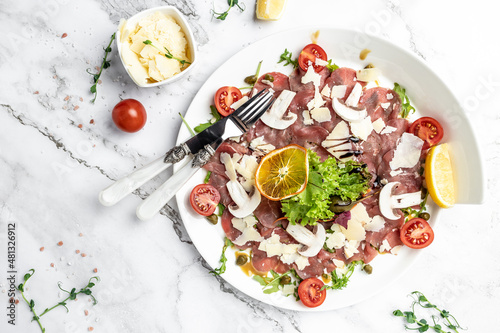 Beef Carpaccio with parmesan, capers and arugula. cold appetizer. banner, menu, recipe place for text, top view.