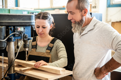 male and female carpenter at work, man and woman are crafting with wood in a workshop photo