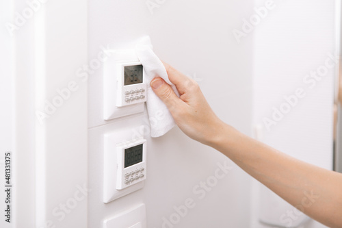 Cleaning switches and sockets with a microfiber cloth. Sanitize surfaces prevention in hospital and public spaces against corona virus. Woman hand using wet wipe for cleaning home room door link.