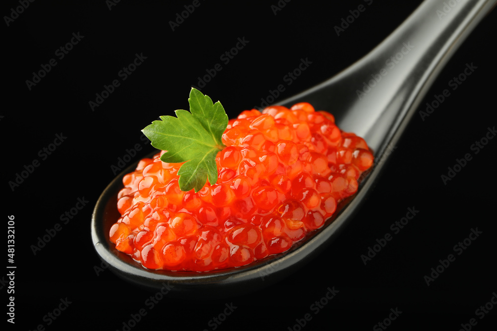 Spoon with delicious red caviar and parsley on black background, closeup Spoon with delicious red caviar and parsley on black background, closeup