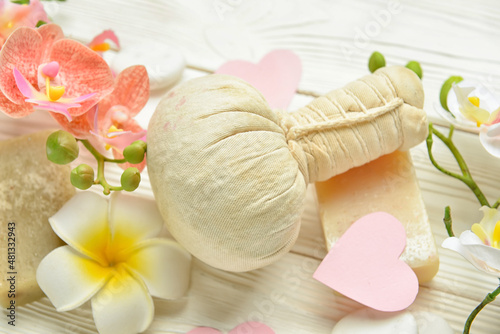 Herbal pouch and flowers for Valentine s Day celebration on light wooden background  closeup