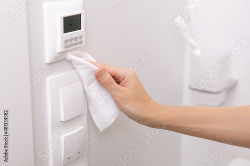 Cleaning switches and sockets with a microfiber cloth. Sanitize surfaces prevention in hospital and public spaces against corona virus. Woman hand using wet wipe for cleaning home room door link.