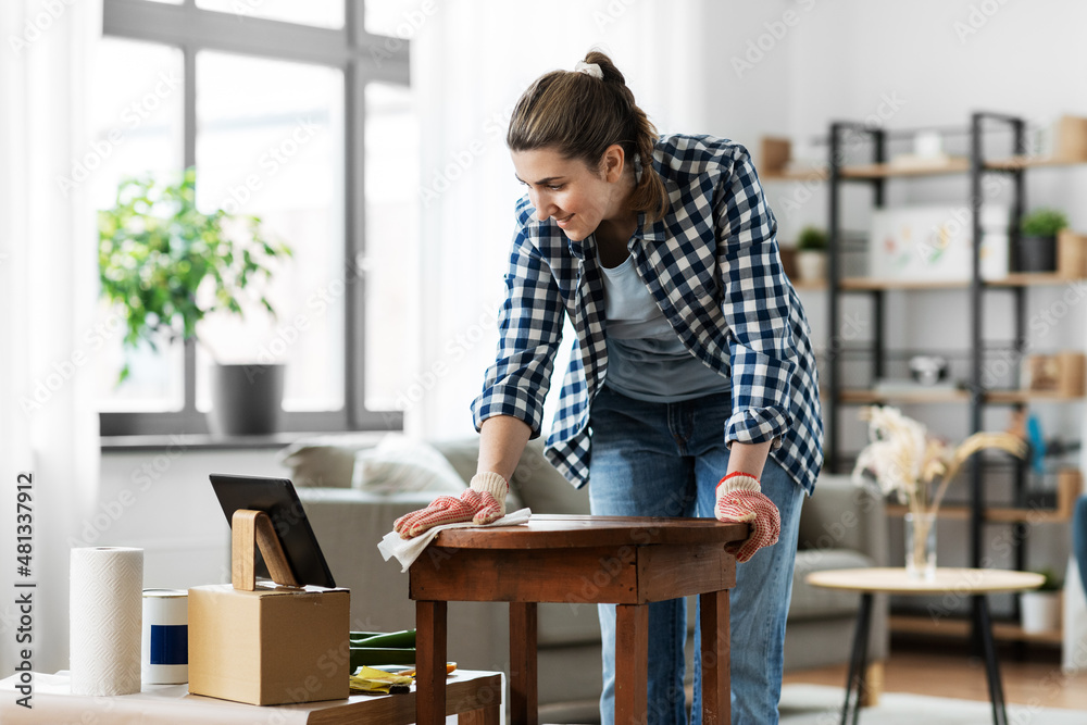 renovation, diy and home improvement concept - happy smiling woman looking at tablet pc computer degreasing old wooden table surface with paper tissue renovation, diy and home improvement concept - happy smiling woman looking at tablet pc computer degreasing old wooden table surface with paper tissue