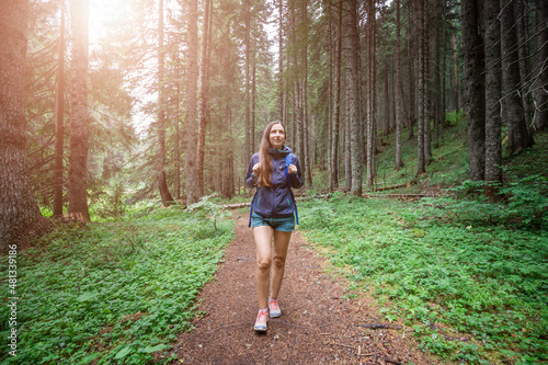 Young smiling woman walking on footpath in the forest.