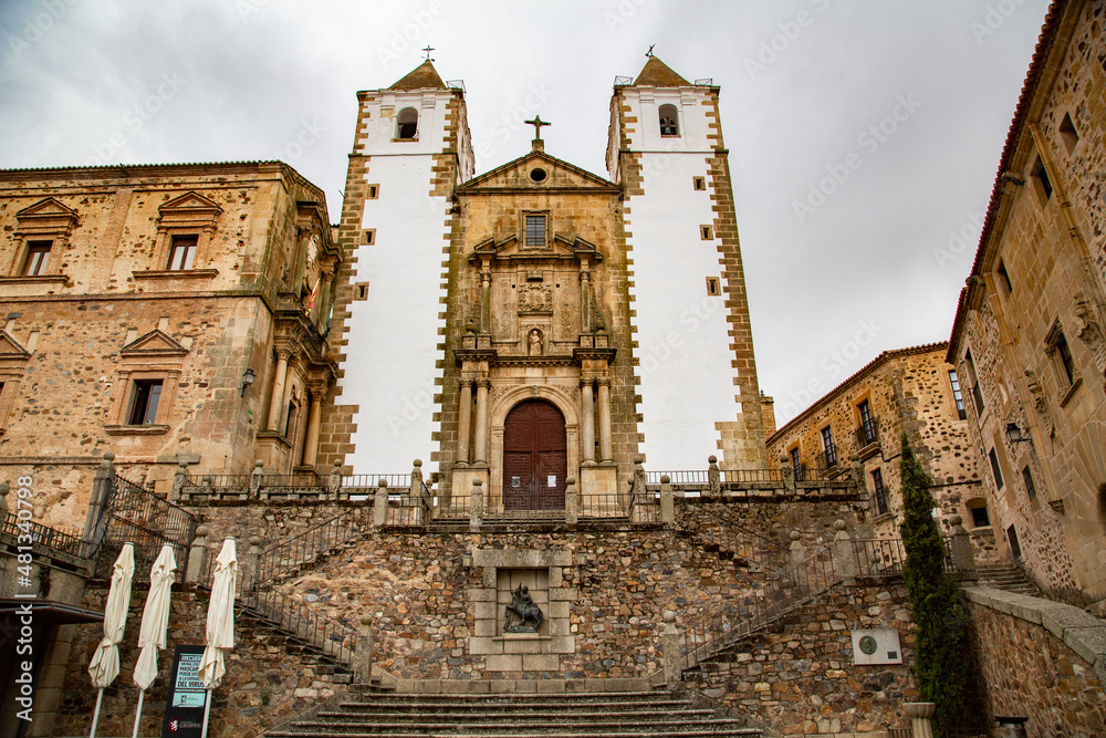 Fachada y acceso a Iglesia de torres de piedra con fachada blanca en Cáceres
