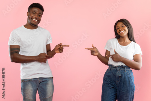 Excited black couple pointing fingers aside at each other