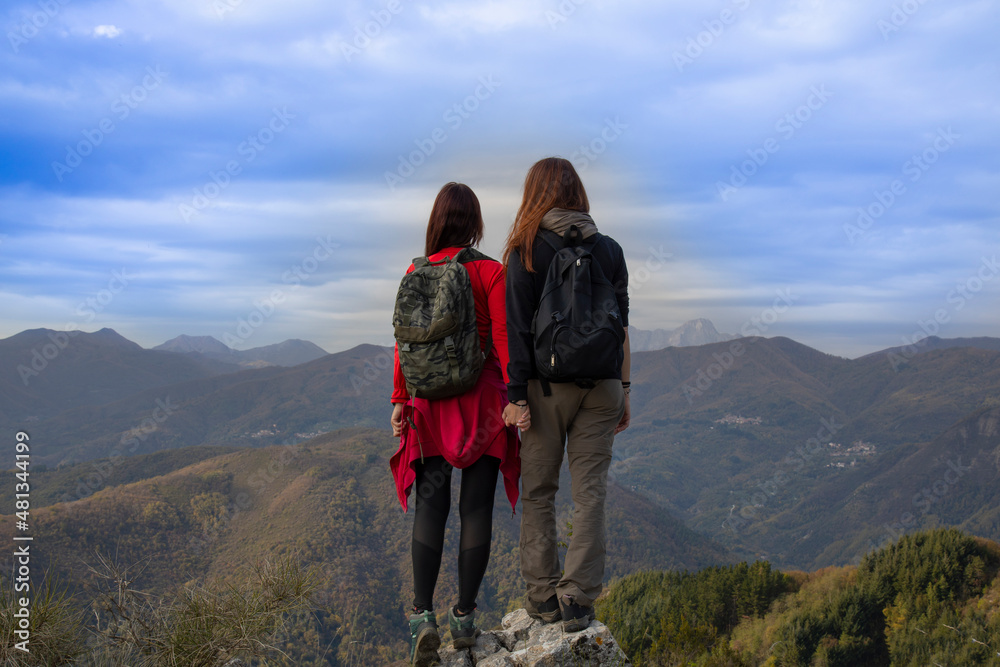 Two  women on top of a mountain in Italy, back view