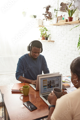 Black man and woman using and typing on laptops