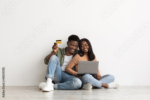 Cheerful african american couple using laptop and credit card