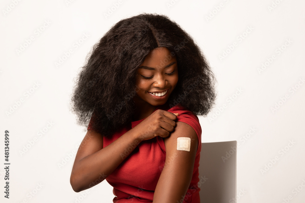 Immunization Concept. Vaccinated Black Female Looking At Her Arm With Adhesive Bandage Immunization Concept. Vaccinated Black Female Looking At Her Arm With Adhesive Bandage