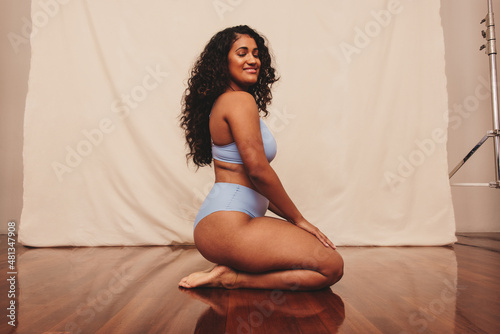 Fototapeta Smiling young woman kneeling in blue underwear