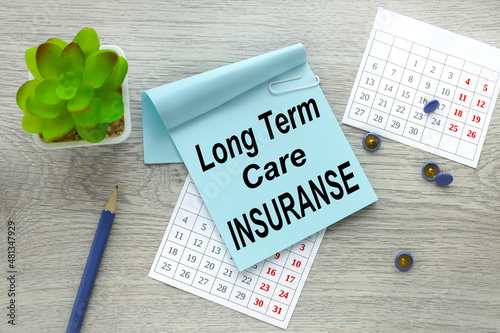 Long-Term Care Insurance. Paper notes on a calendar with copy space for your work or new idea. workplace with office supplies on a wooden table.