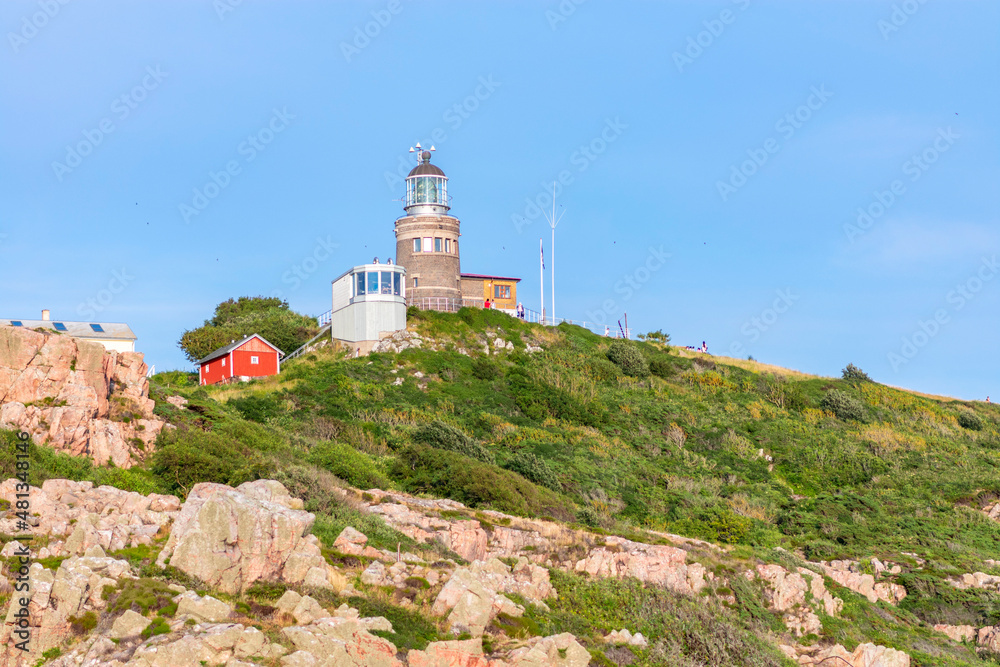 Kullaberg fyr, old lighthouse on the cliffs of Kullaberg naturreservat on the Swedish west coast. Lighthouse on the rocks viewing out into the baltic sea. Warm summer, high cliffs, deap ocean. Trees