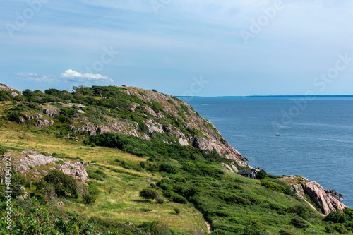 Cliff of Kullaberg mountain on the west coast of Sweden. Klippa på Kullaberg. Baltic sea in the distance behind the dramatic rocks. Sunshine on a warm summer day, Scandinavia. 